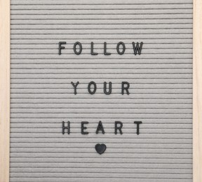 Photo of Letter board with phrase Follow your heart on white background, top view