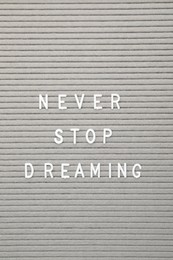 Letter board with phrase Never stop dreaming as background, top view