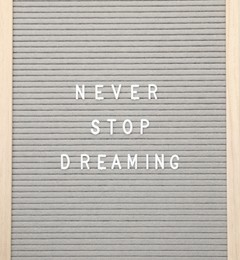 Photo of Letter board with phrase Never stop dreaming on white background, top view