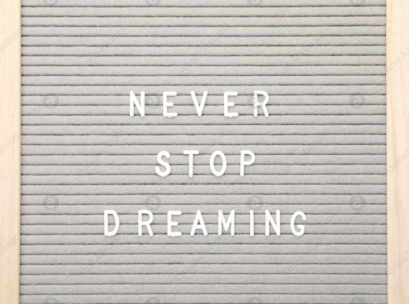 Photo of Letter board with phrase Never stop dreaming on white background, top view