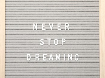 Letter board with phrase Never stop dreaming on white background, top view