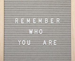 Photo of Letter board with phrase Remember who you are on white background, top view