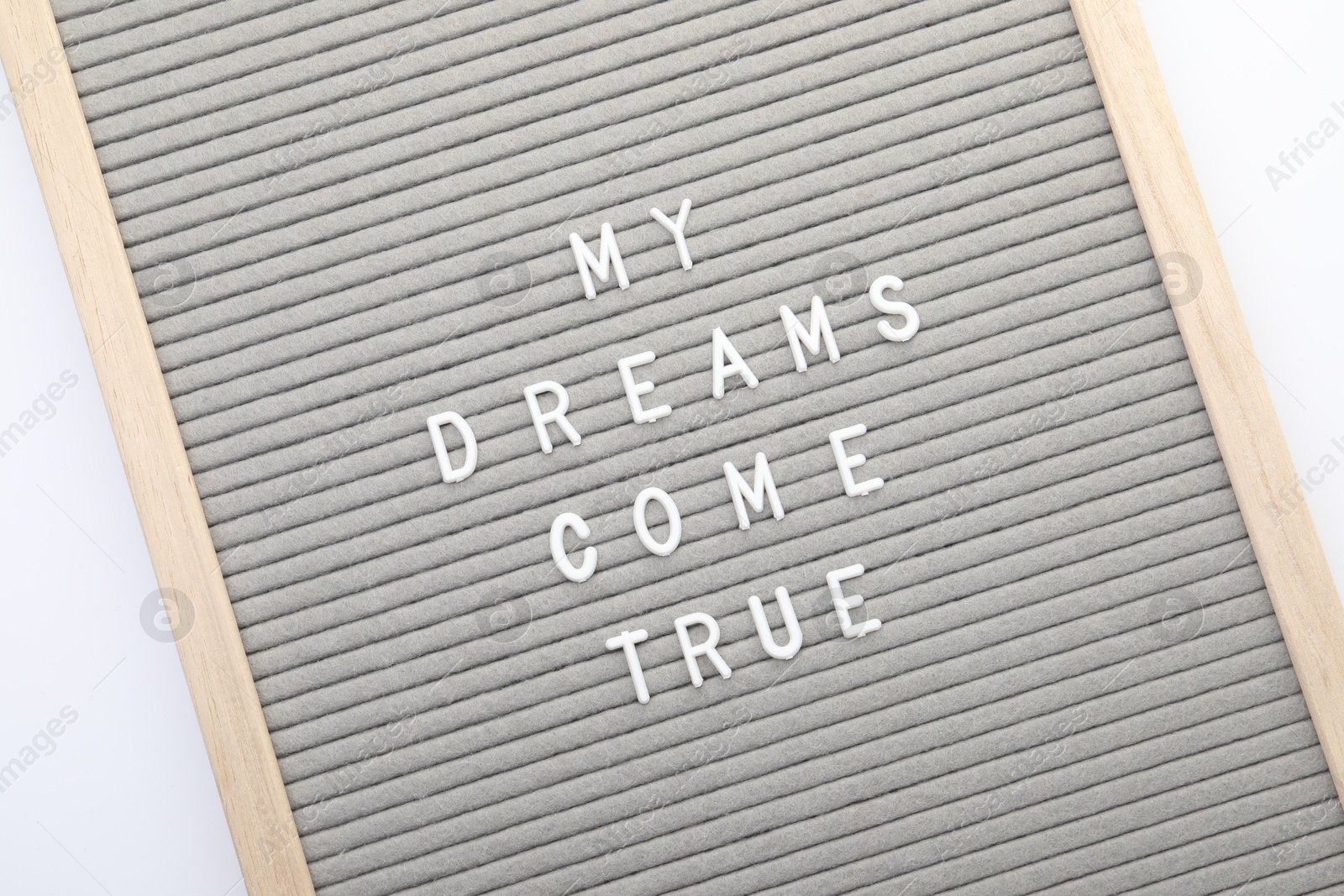 Photo of Letter board with phrase My dreams come true on white background, top view