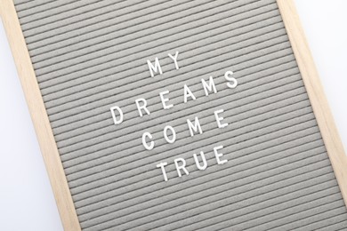 Photo of Letter board with phrase My dreams come true on white background, top view