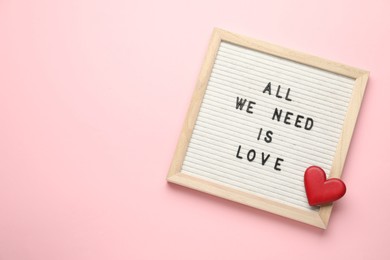 Photo of Letter board with phrase All We Need Is Love and decorative heart on pink background, top view. Space for text