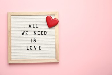 Photo of Letter board with phrase All We Need Is Love and decorative heart on pink background, top view. Space for text