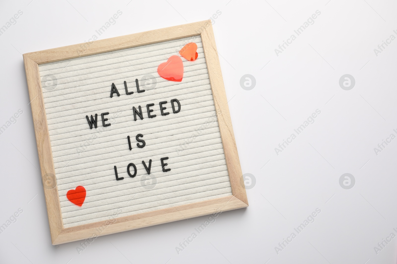 Photo of Letter board with phrase All We Need Is Love and decorative heart on white background, top view. Space for text