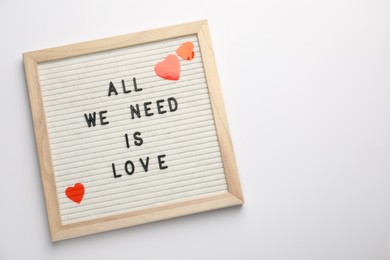 Photo of Letter board with phrase All We Need Is Love and decorative heart on white background, top view. Space for text