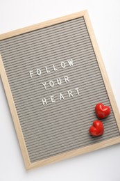 Letter board with phrase Follow Your Heart and decorative hearts on white background, top view