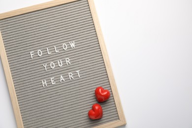 Photo of Letter board with phrase Follow Your Heart and decorative hearts on white background, top view. Space for text