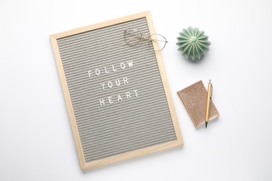 Letter board with phrase Follow Your Heart, glasses, notebook, cactus figure and pen on white background, flat lay