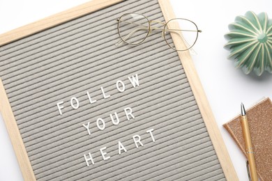 Photo of Letter board with phrase Follow Your Heart, glasses, notebook, cactus figure and pen on white background, flat lay