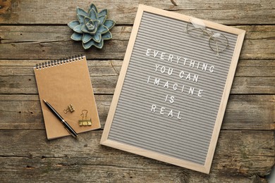 Photo of Letter board with phrase Everything You Can Imagine Is Real, stationery, glasses, succulent, pen and binder clips on wooden background, flat lay