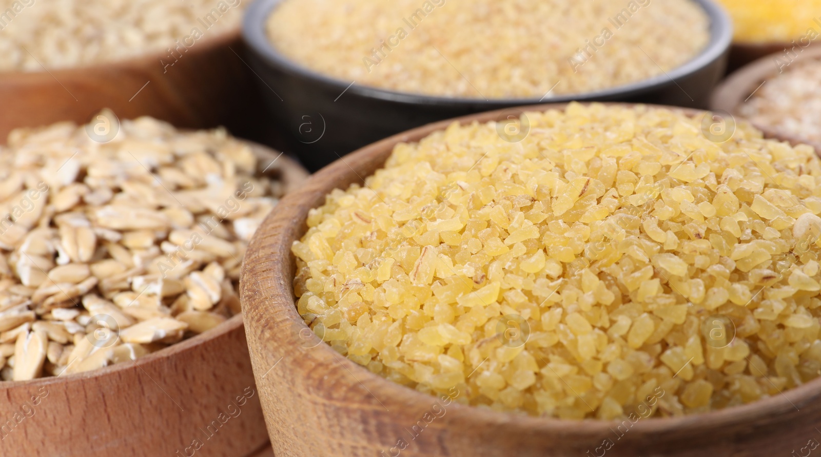 Photo of Different types of cereals in bowls on table, closeup