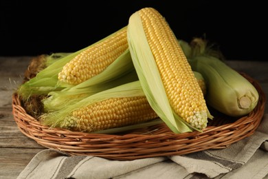 Photo of Many fresh ripe corncobs with green husks on wooden table