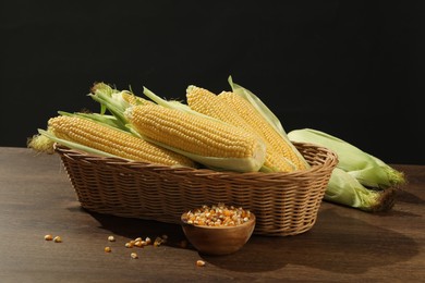 Many fresh ripe corncobs with green husks and kernels on wooden table