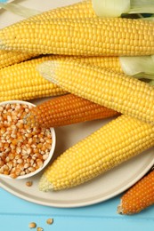 Many corncobs and kernels on light blue wooden table, top view