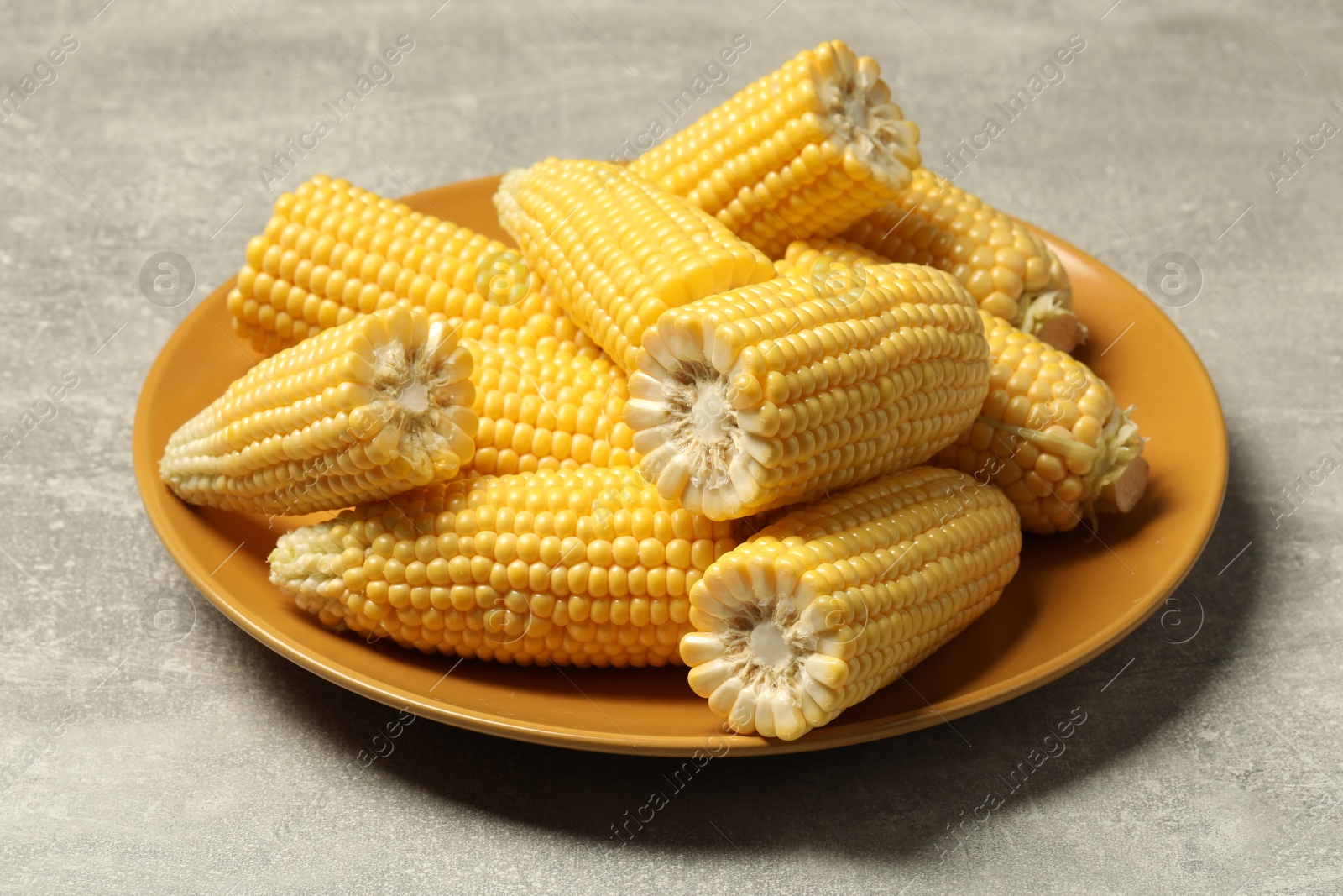 Photo of Halves of fresh ripe corncobs on grey table