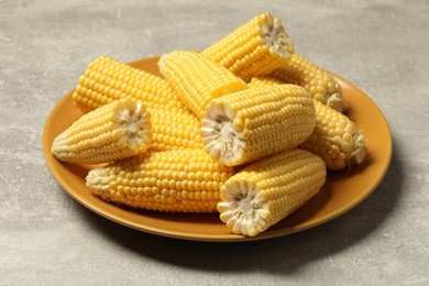 Halves of fresh ripe corncobs on grey table