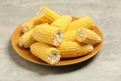 Halves of fresh ripe corncobs on grey table