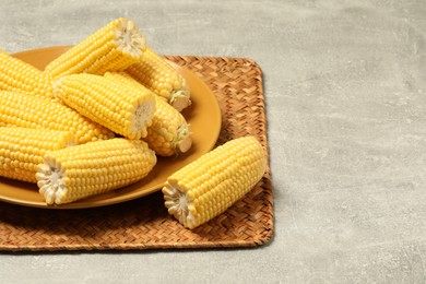 Photo of Halves of fresh ripe corncobs on grey table. Space for text