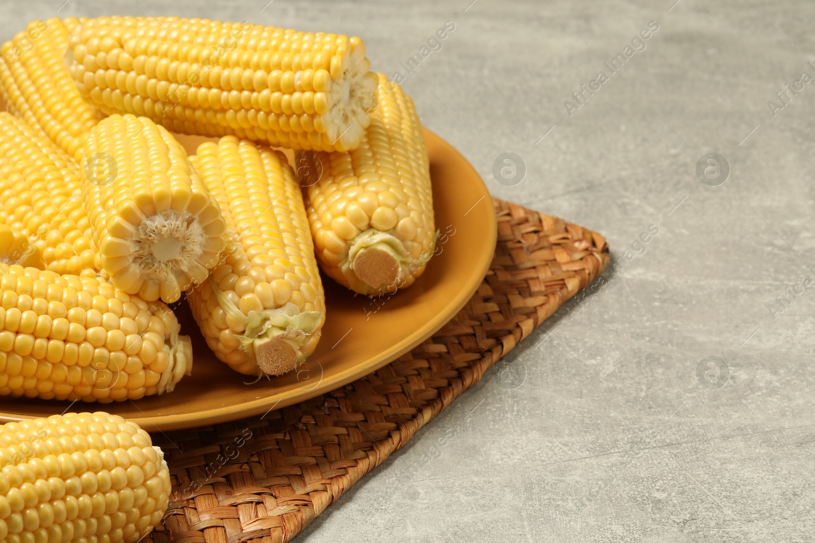 Photo of Halves of fresh ripe corncobs on grey table, closeup. Space for text