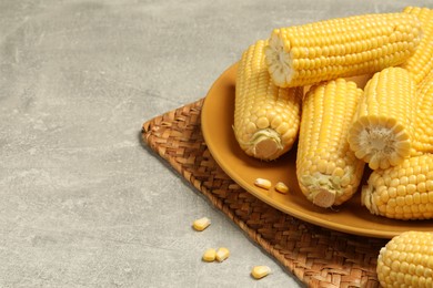 Photo of Halves of fresh ripe corncobs on grey table, closeup. Space for text