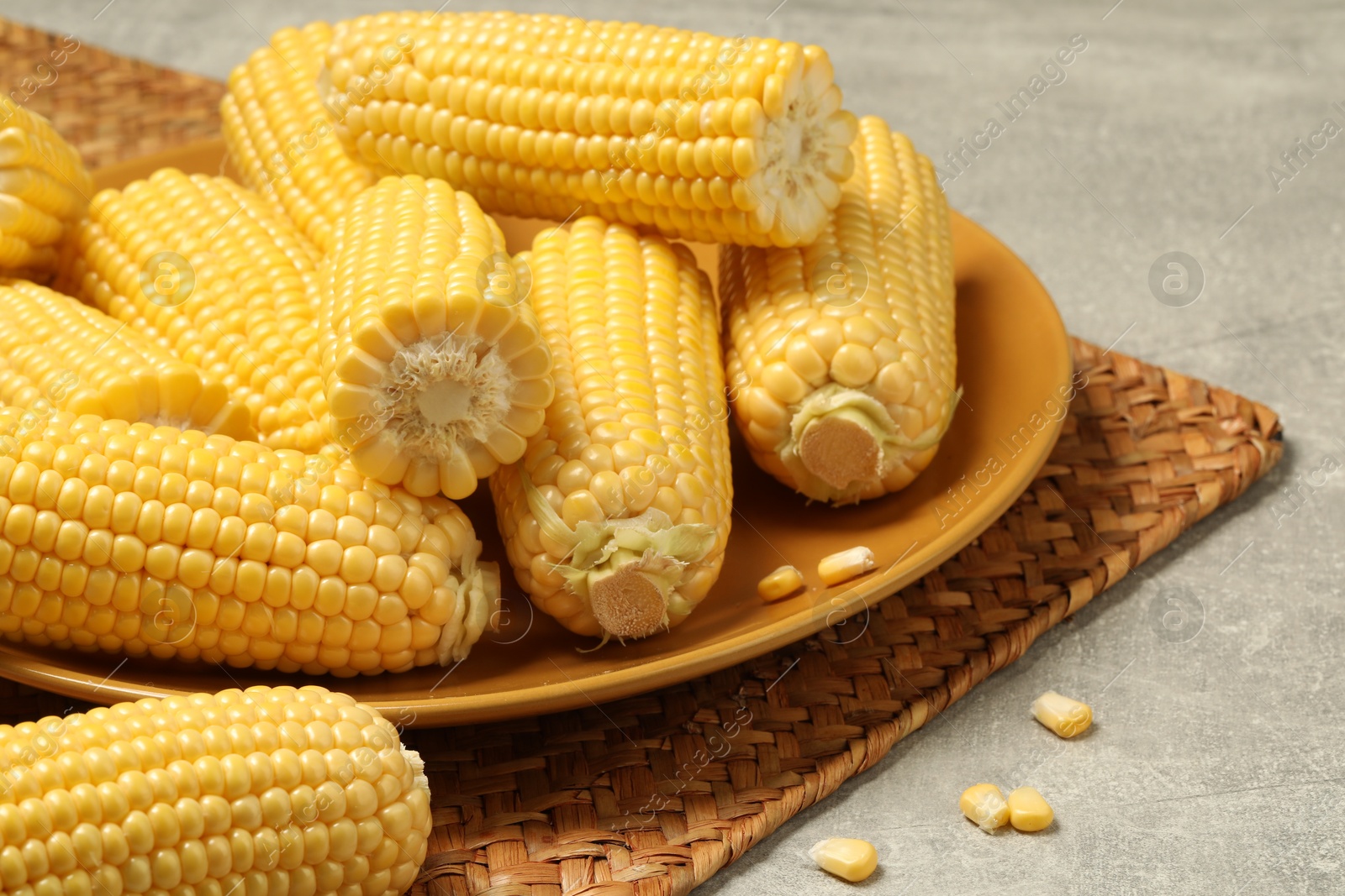 Photo of Halves of fresh ripe corncobs on grey table, closeup