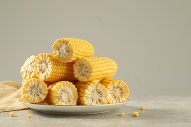 Photo of Halves of fresh ripe corncobs on grey table. Space for text