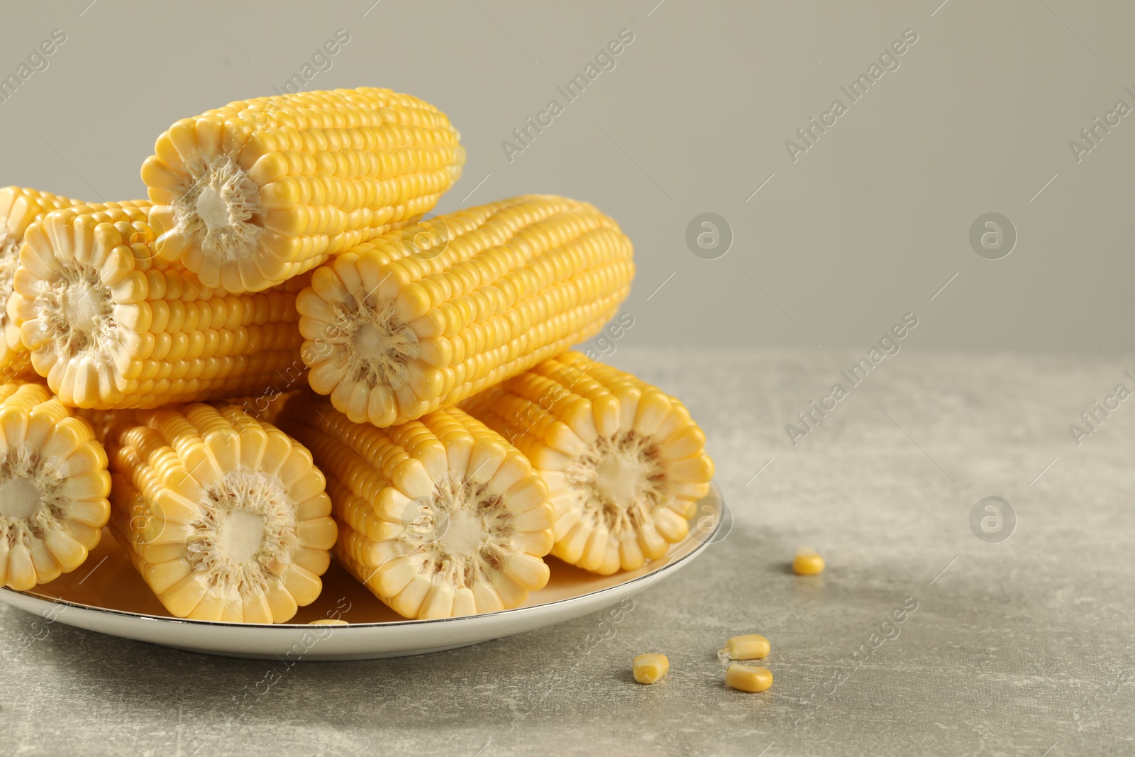 Photo of Halves of fresh ripe corncobs on grey table, closeup. Space for text