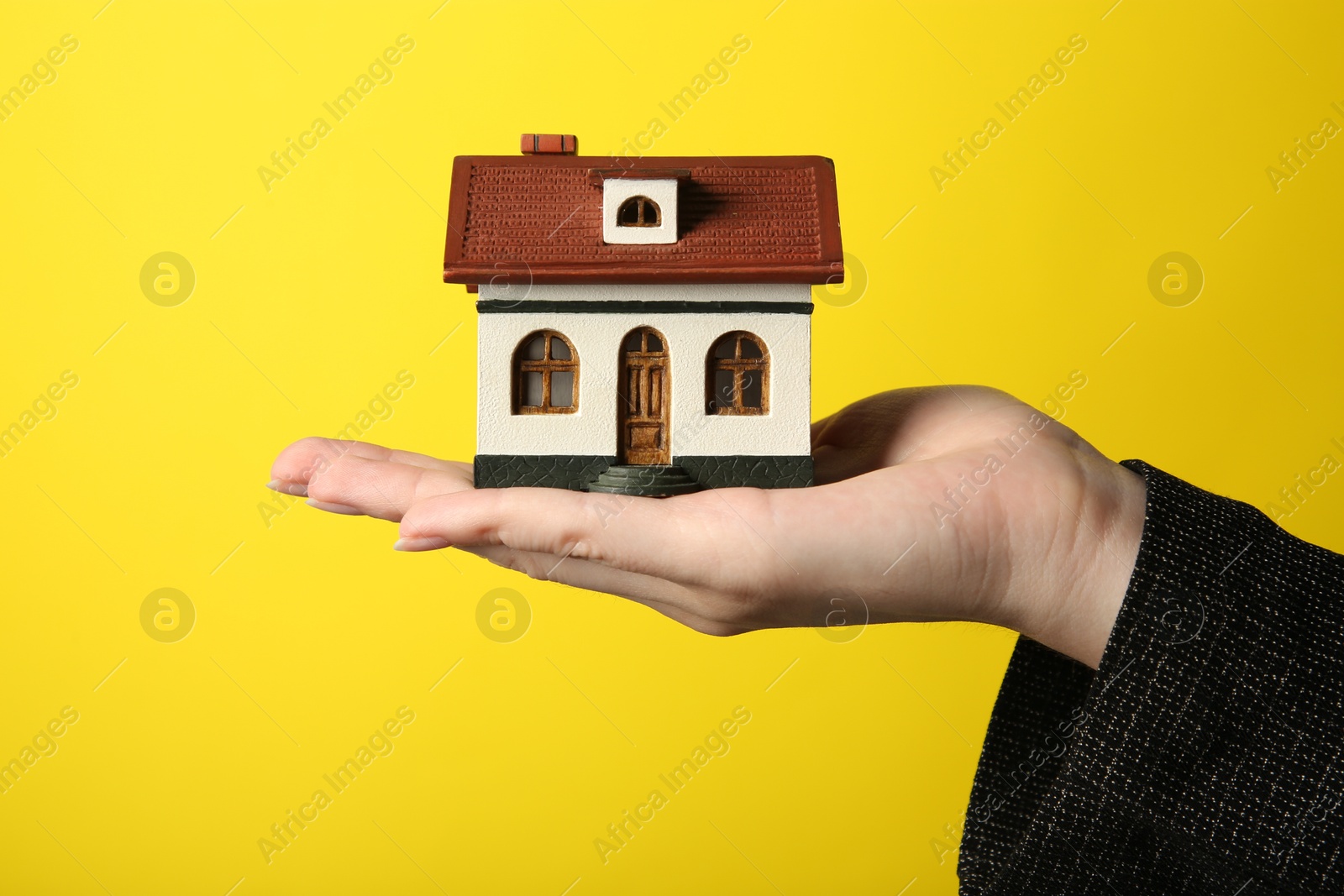 Photo of Woman with house model on yellow background, closeup