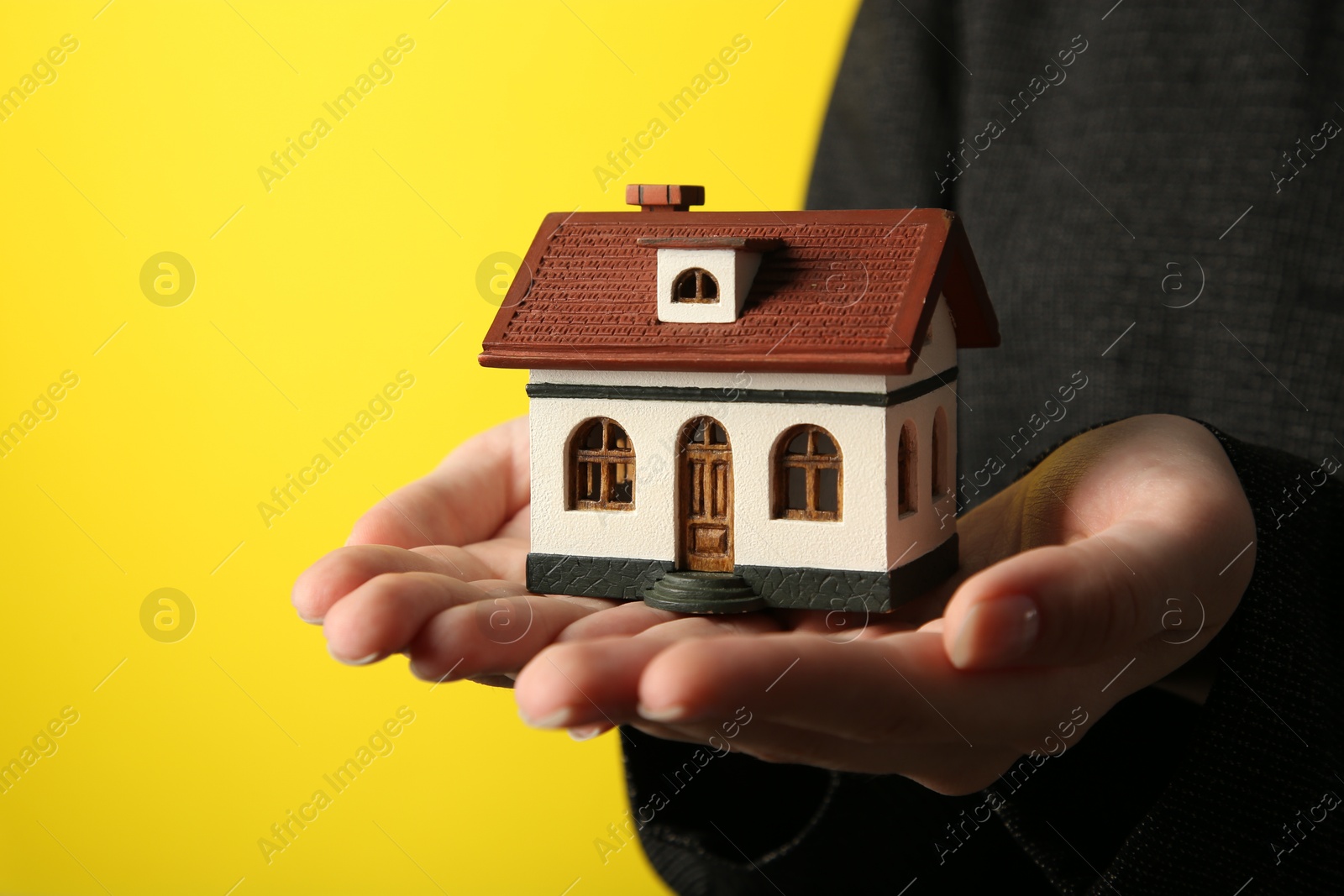 Photo of Woman with house model on yellow background, closeup