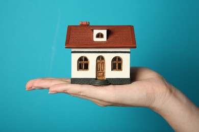 Photo of Woman with house model on light blue background, closeup