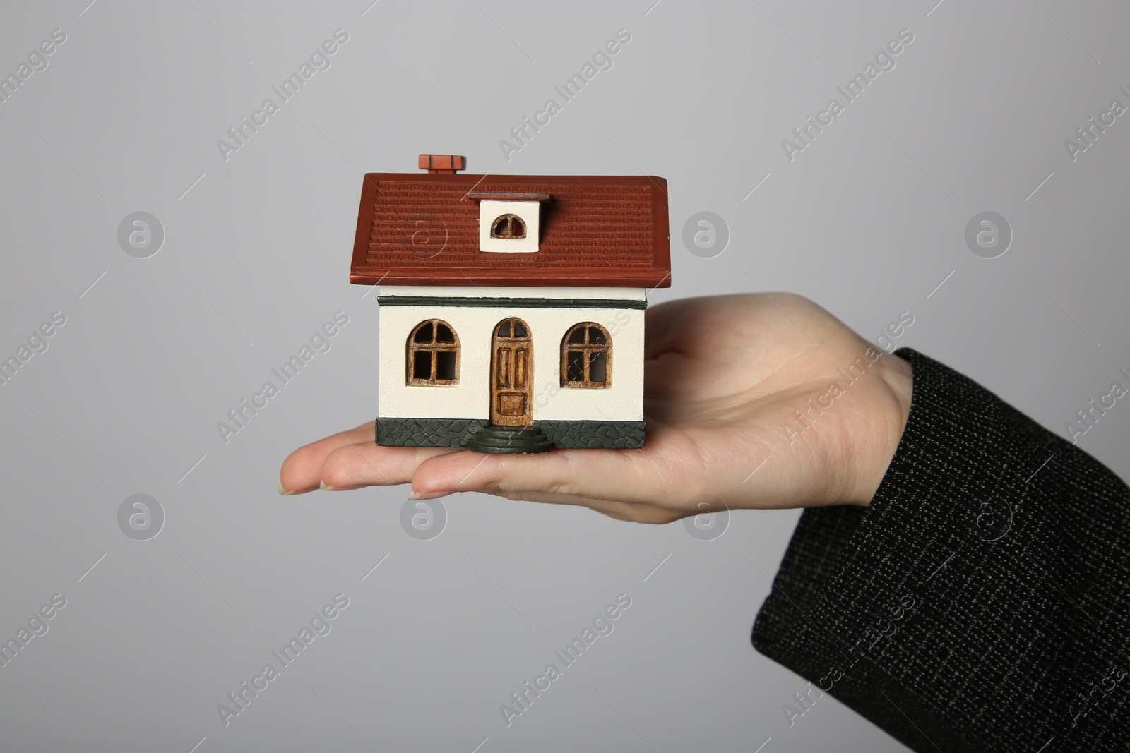 Photo of Woman with house model on grey background, closeup