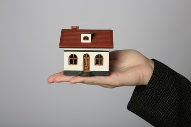 Photo of Woman with house model on grey background, closeup