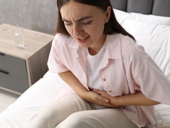 Woman suffering from menstrual pain on bed at home