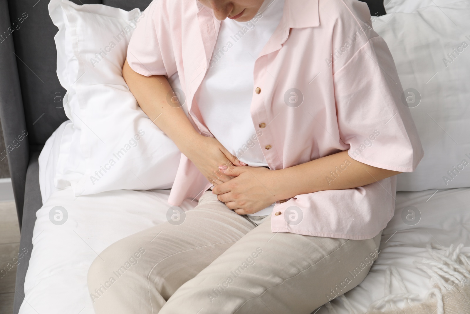 Photo of Woman suffering from menstrual pain on bed at home, closeup