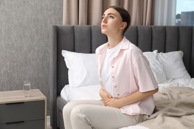 Woman suffering from menstrual pain on bed at home