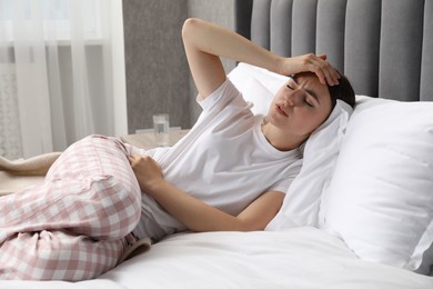 Woman suffering from menstrual pain on bed at home