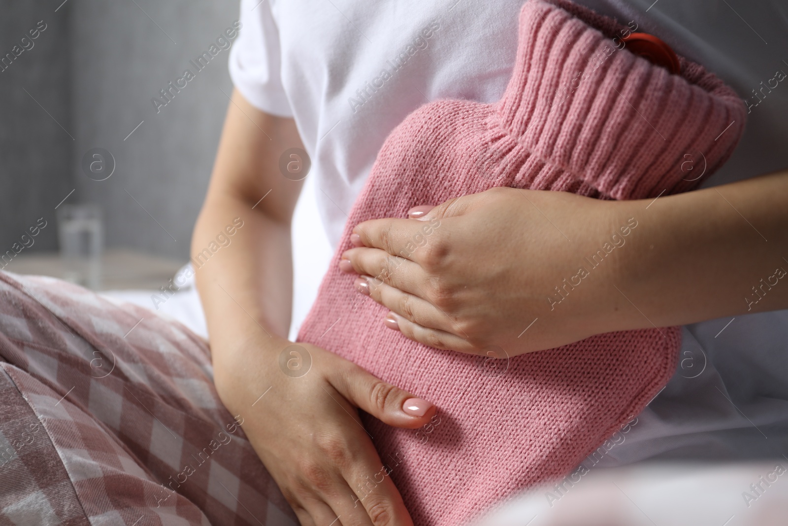 Photo of Woman using hot water bottle to relieve menstrual pain at home, closeup