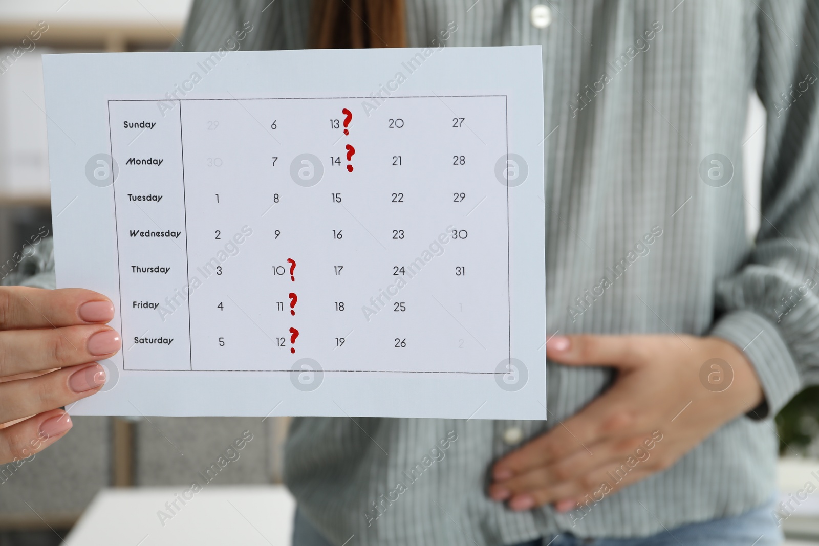 Photo of Woman holding calendar with marked menstrual cycle days and suffering from abdominal pain indoors, closeup