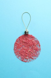 Photo of Christmas ball made with blush on light blue background, top view