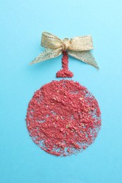 Photo of Christmas ball made with blush on light blue background, top view