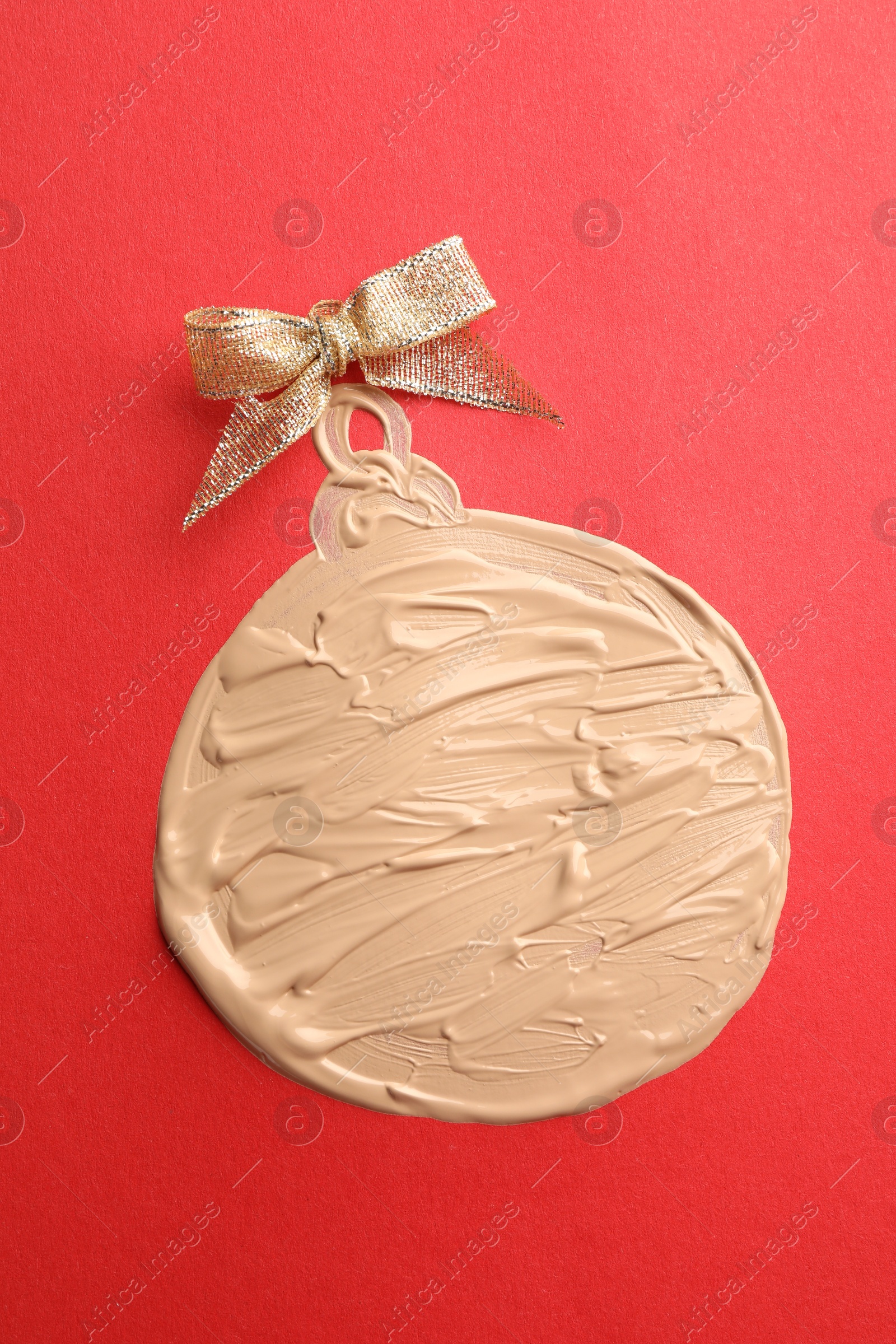 Photo of Christmas ball made of skin foundation on red background, top view