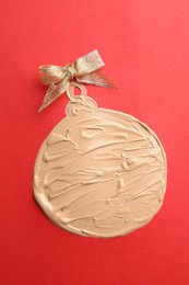 Christmas ball made of skin foundation on red background, top view