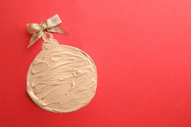 Photo of Christmas ball made of skin foundation on red background, top view. Space for text