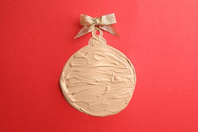 Photo of Christmas ball made of skin foundation on red background, top view