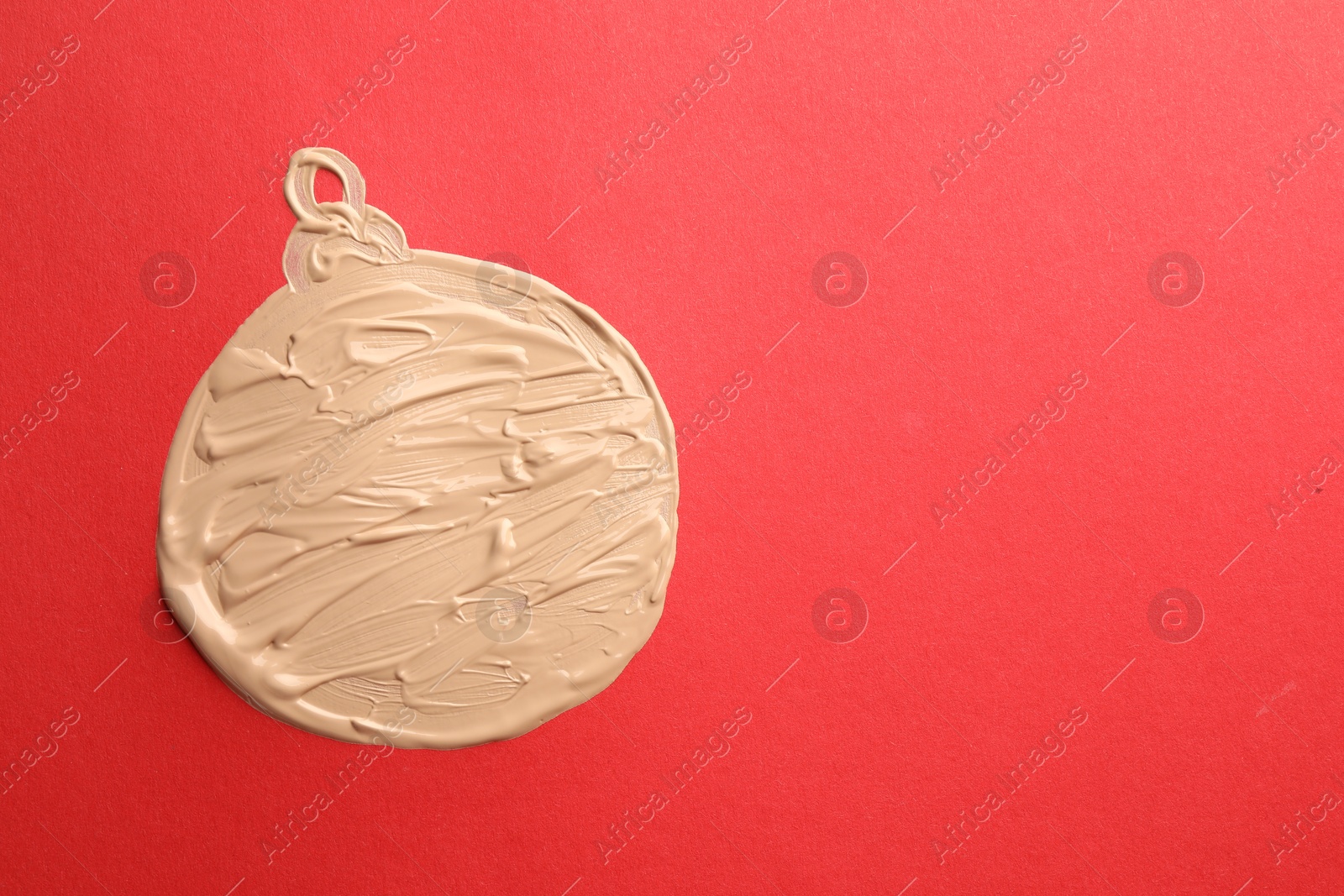 Photo of Christmas ball made of skin foundation on red background, top view. Space for text