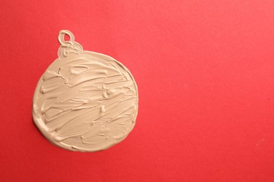 Christmas ball made of skin foundation on red background, top view. Space for text