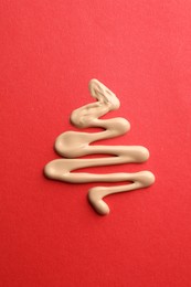 Photo of Christmas tree made of skin foundation on red background, top view